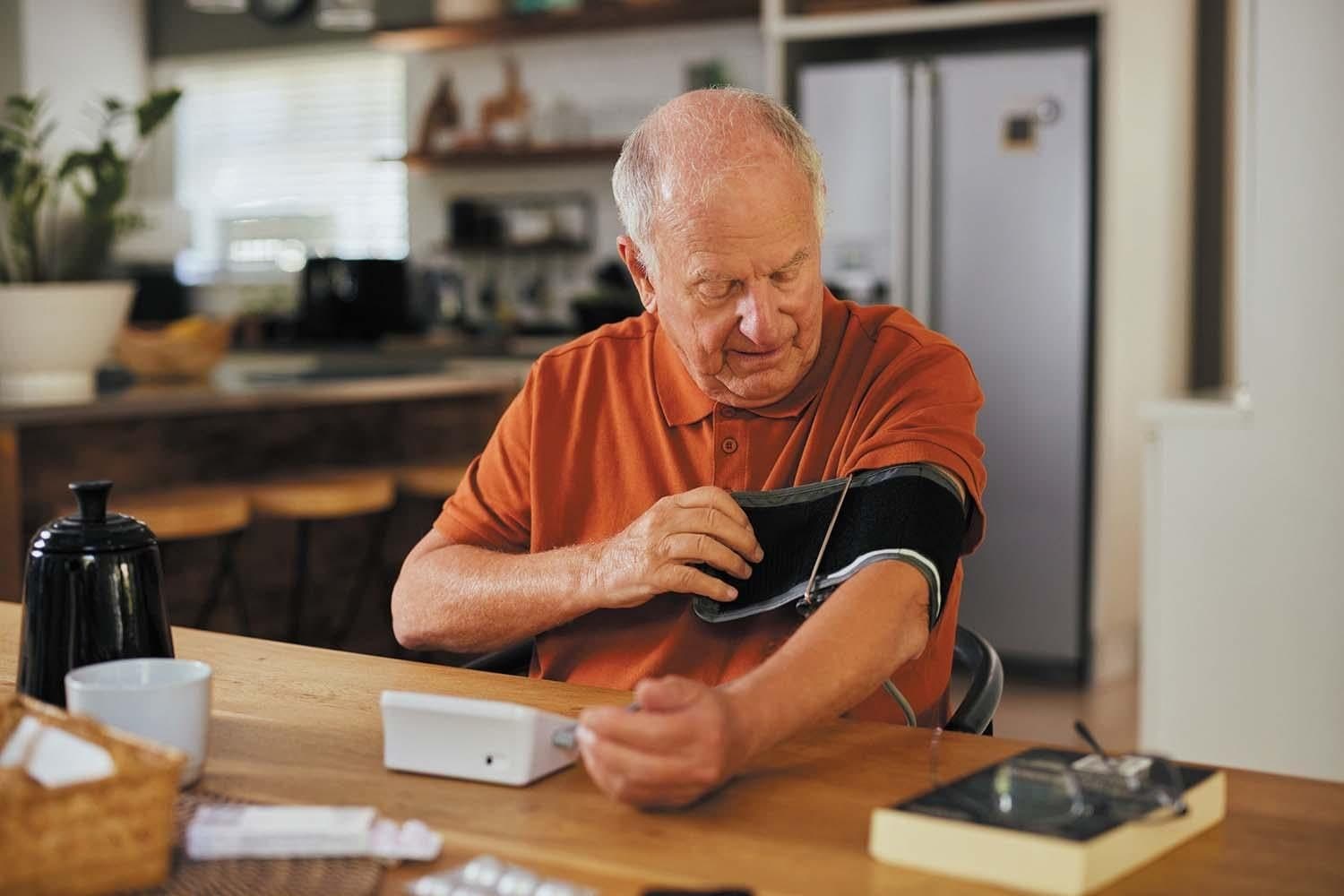 A man fitting a blood pressure cuff at his own kitchen table