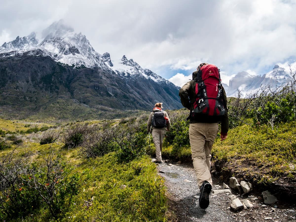 Two walkers on a mountain trail, seen from behind